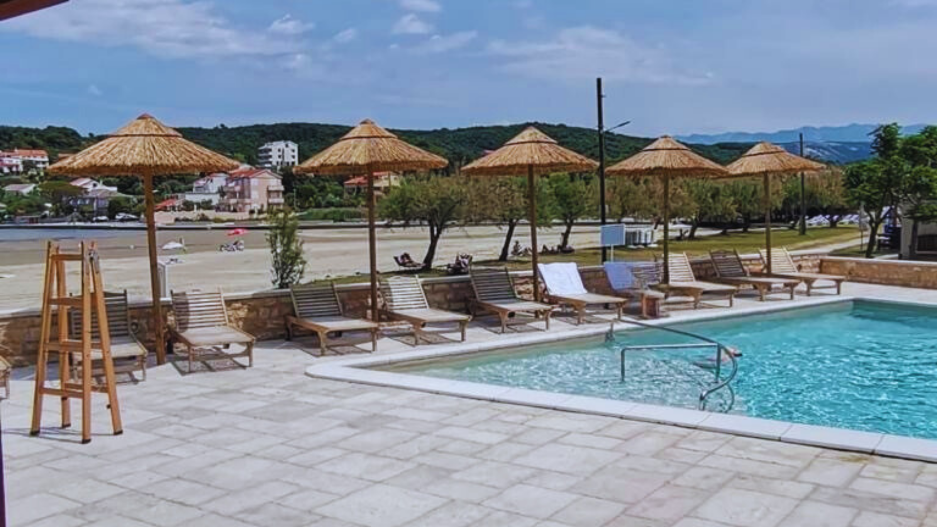Suncobrani uz bazen i ležaljke u turističkom objektu